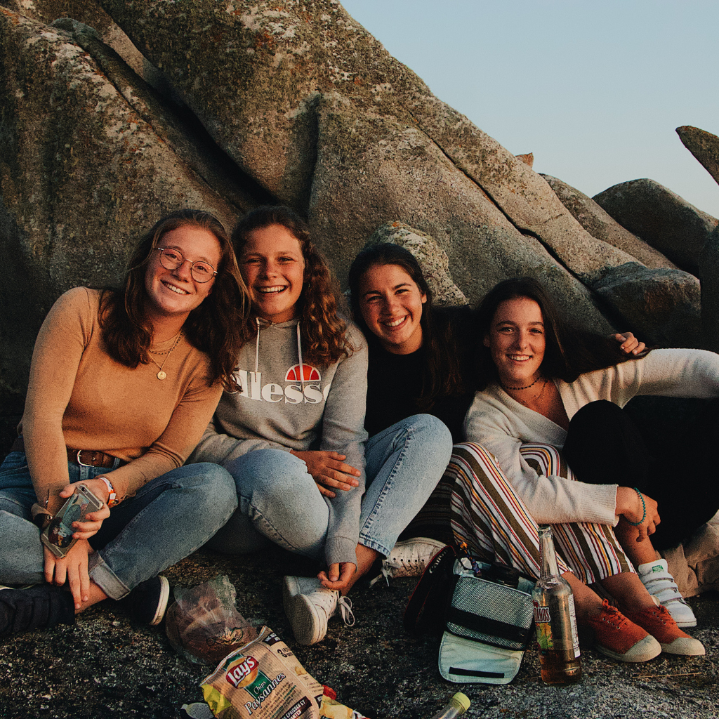Quatre amies partagent un verre assises sur des rochers